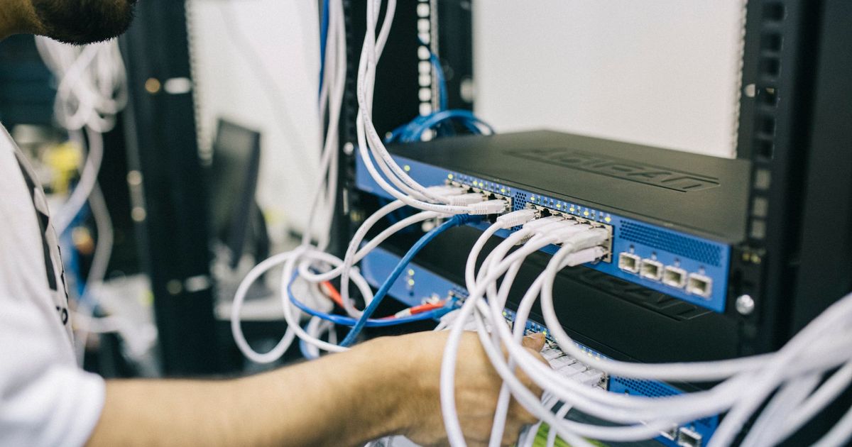 Technicus sluit netwerkkabels aan op een switch in een rack