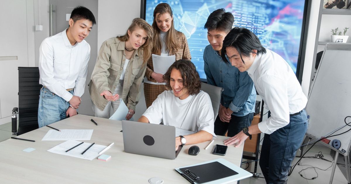 Een man legt zijn team iets uit op een laptop