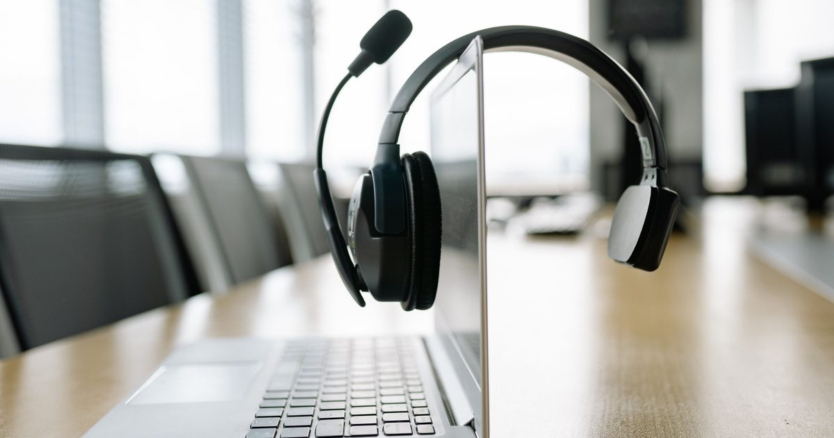 Een headset met microfoon hangt over het scherm van een laptop op een vergadertafel