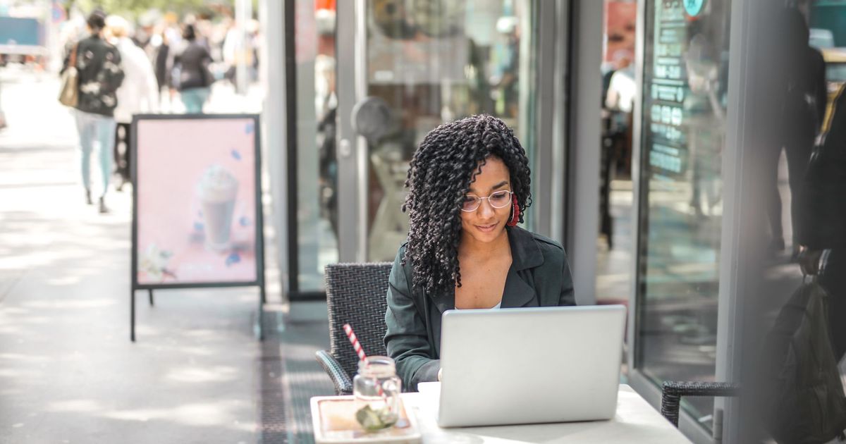Een vrouw werkt op haar laptop op een caféterras