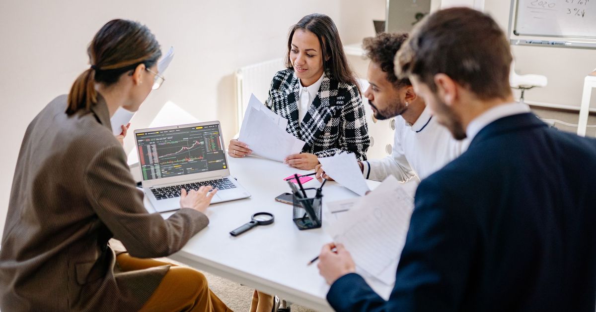 Collega's werken samen aan een laptop rond een tafel
