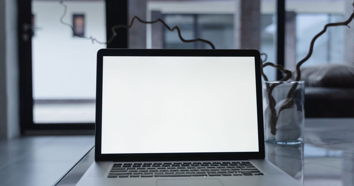 Open laptop met een wit scherm op een glazen tafel