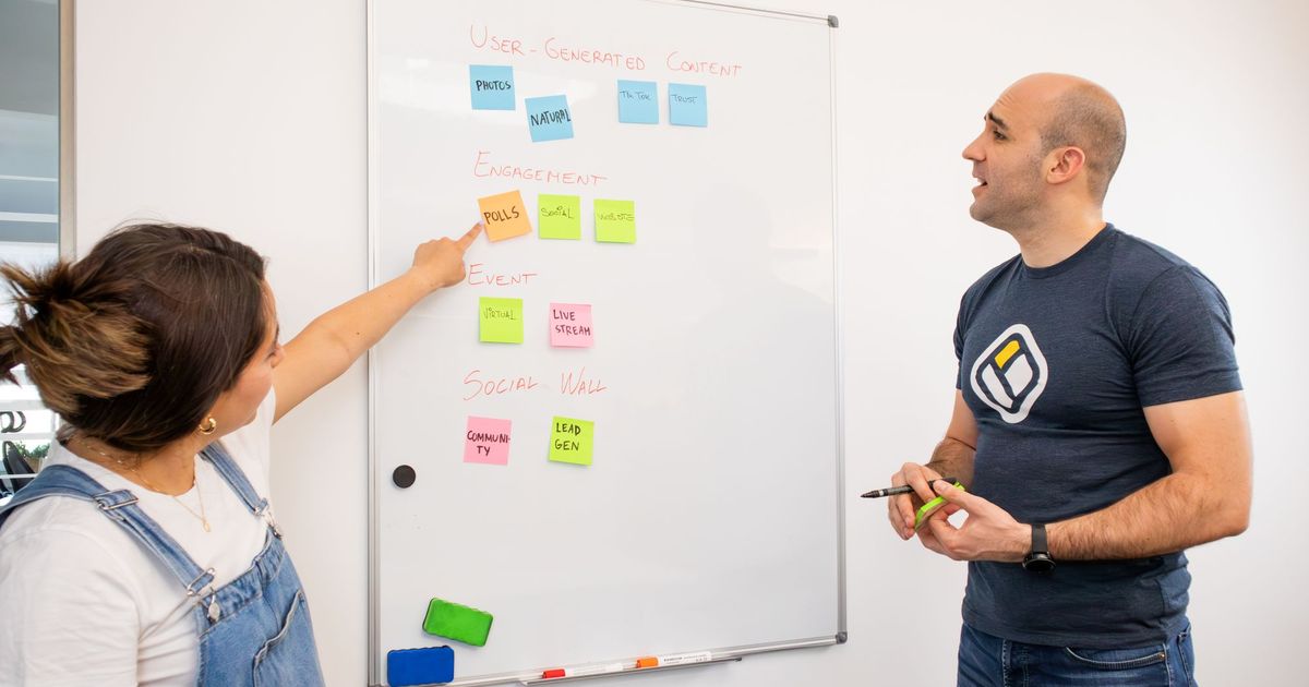 Twee collega's plannen samen aan een whiteboard met post-its