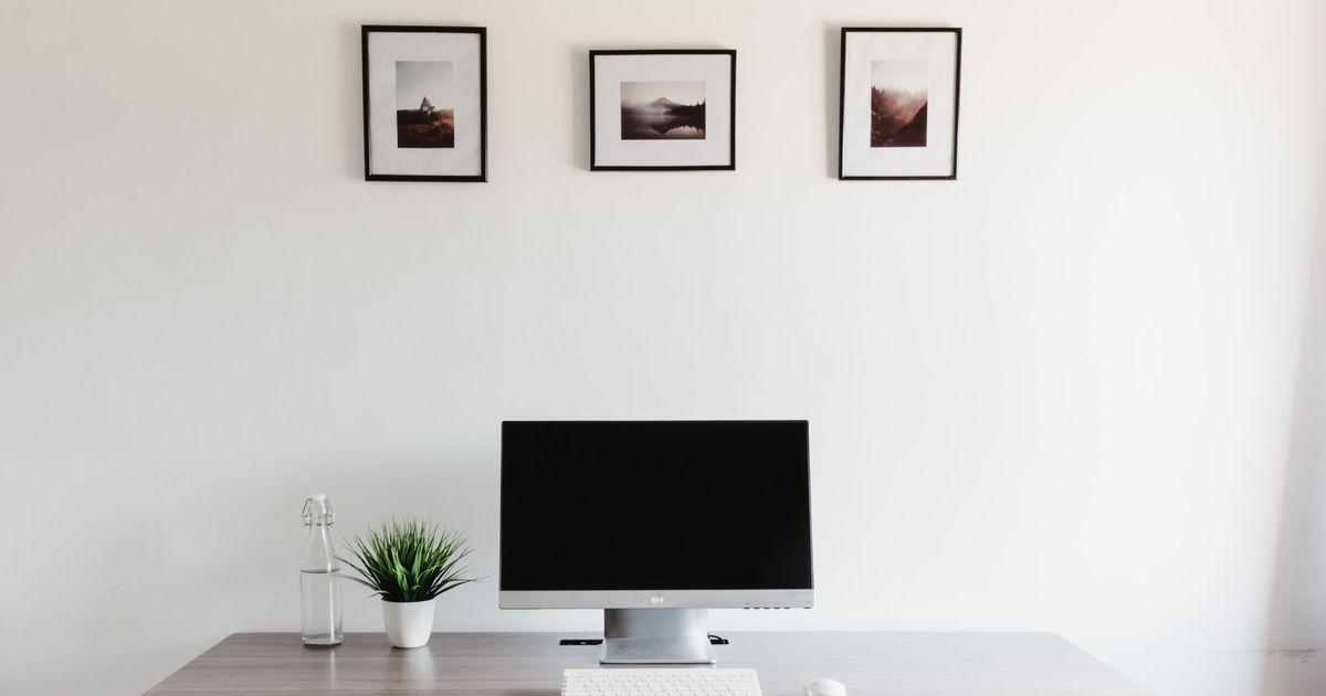 Strakke, minimalistische werkplek met een computerscherm tegen een witte muur