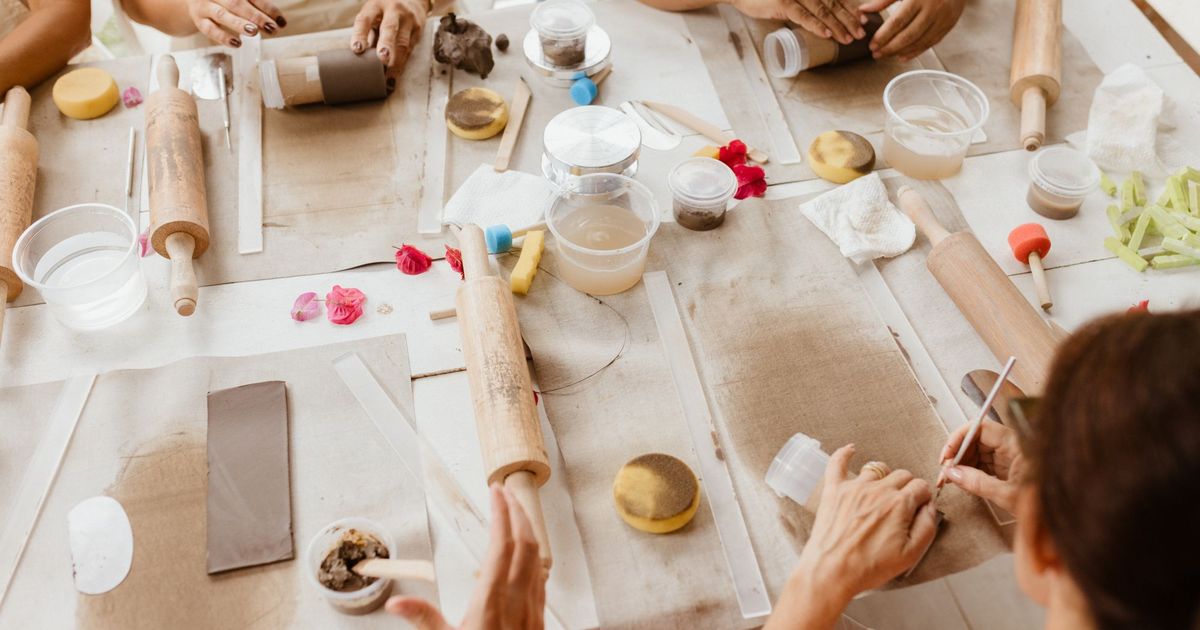 Een groep mensen werkt samen met klei aan een tafel tijdens een workshop
