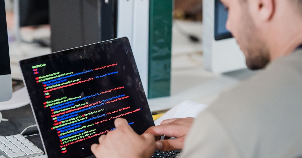 Een man werkt in een kantoor aan code op een laptop