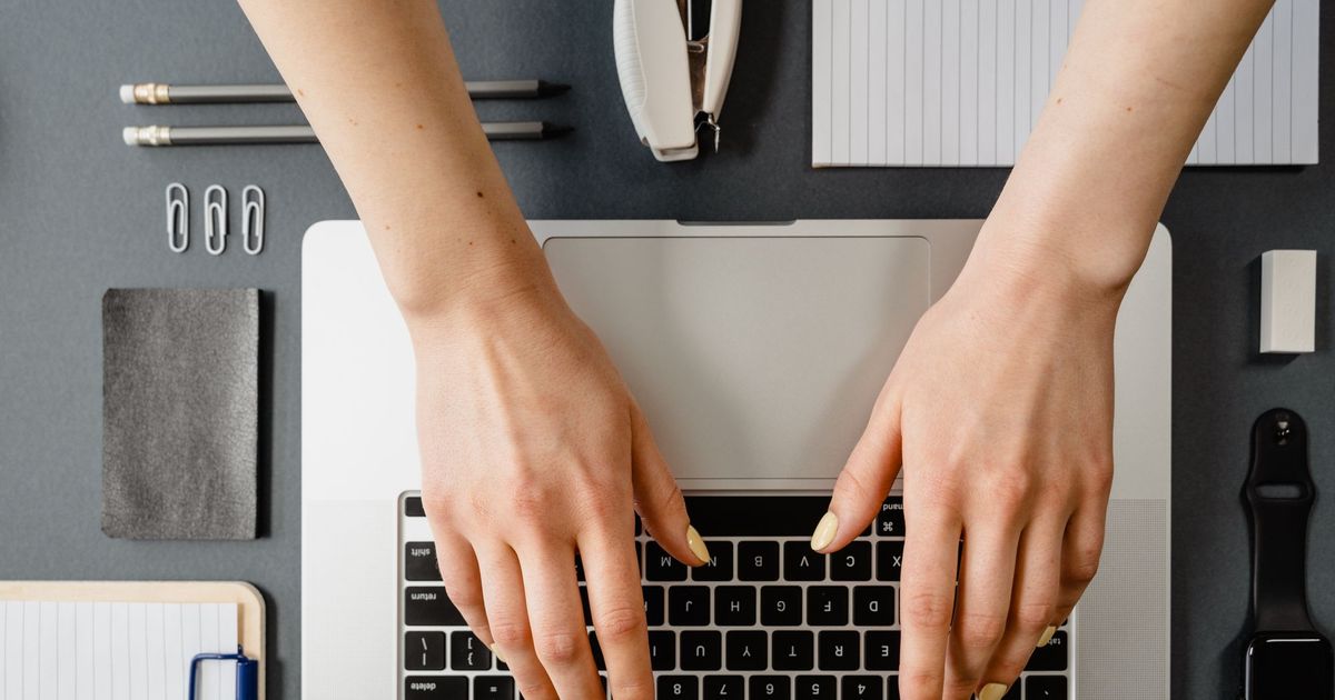 Handen typen op een laptop, van bovenaf gezien