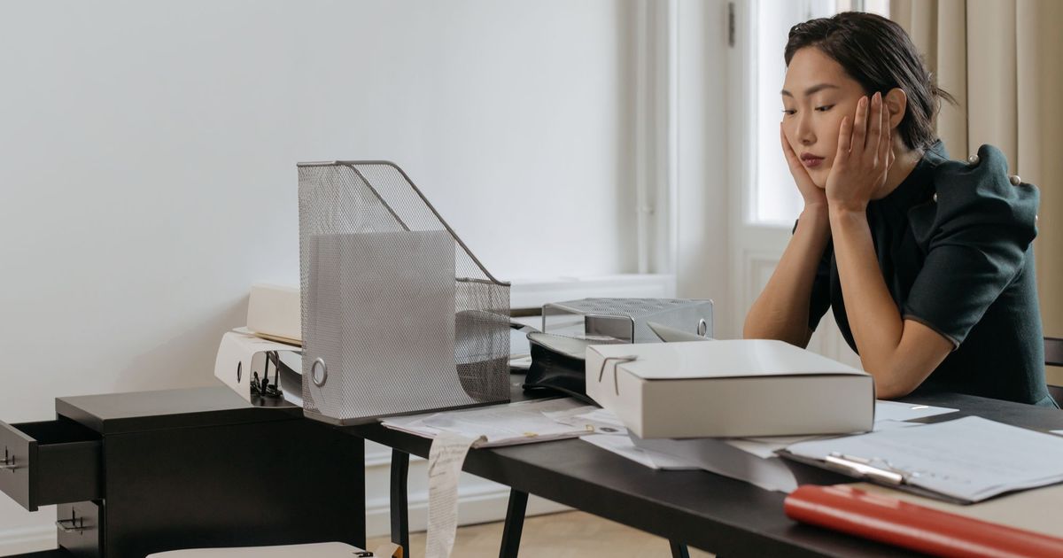 Een vrouw zit gefrustreerd aan haar bureau op kantoor